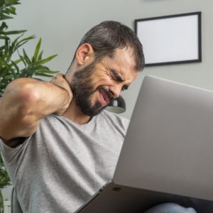 man-experiencing-neck-pain-while-working-from-home-on-laptop